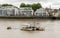 A small rusty floating pier in dirty waters of river Thames in front residential houses on the banks, London, England