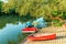 Small sail and pedal boats parked by river bank at summer sunset. Water attractions and water vehicle rental service in park