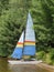 Small sailboat on shore of a lake.