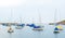 Small sailboats anchored in the harbor behind a rocky breakwater in Rockport, Massachusetts