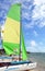 Small sailing catamaran with yellow and green sails