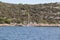 A small sailing trimaran on the background of the stony shore of the Croatian Riviera. The green island of the Adriatic Sea in Dal