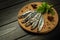 A small salted anchovy or sprat with spices and herbs on a wooden serving board. The idea of a fish diet