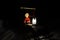 Small santa travelling home on kicksled on snowy road with suitcase and lantern