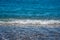 Small sea blue wave reaching a calm beach.