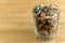 Small sea stones in a glass vessel. The idea of decorating the house with small rocks in a jar on a wooden blurred background