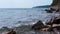 Small sea waves break on the rocks. Beautiful seascape with clear blue sky and calm smooth sea.