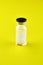 Small sealed bottle with medicine on yellow background