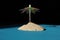 Small self-made holiday island with a colorful parasol on blue ground with black background