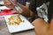 A small serving of lasagne on a square plate, person holds a fork in hand and eats