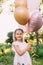 Small shiny girl with pink balloons in the garden