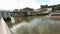 Small sightseeing boat sailing down river, tourists enjoying view of city