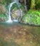 Small silky water fall running over moss covered rocks.