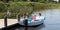 Small single engine motorboat tied to dock with green beach grass in background