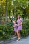 A small smiling girl with curly brown hair dressed in blue red pink dress with zigzag print with young smiling mother