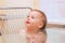 Small smiling white child sitting on a chair at the glass table in the kitchen near the window. The image is reflected from the