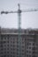 Small snow falls on the background of blurred tower crane and snow-covered construction