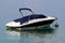 Small speed boat covered with dark blue protection anchored in local harbor surrounded with calm clear blue sea