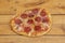 Small spicy pepperoni pizza with cheese, oregano and tomato on varnished wood