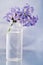 A small sprig of lilac flowers in a small transparent bottle