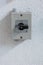 Small square electric switch box with on off markings set on a wall close up shot front view