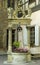 A small stone fountain holding pink flowers with carved angels standing at the top in Colmar, France