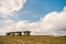 Small stony empty houses on green grass and cloudy sky