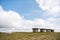 Small stony empty houses on green grass and cloudy sky