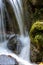 Small stream and waterfall among the moss, vegetation and rocks