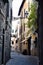 Small street with a historic building, a wall lamp and green branches in Pistoia near the city center.