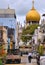 Small street with old colorful buildings, motorcycles and cars with chaotic traffic, old mosque with golden dome in background in