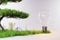 Small strip of growing plants and trees with standing light bulb, nature on neutral grey background; conceptual energy saving; 3D