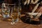 Small tasting glasses with aged Scotch whisky on old dark wooden vintage table with barley grains