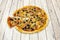 Small thin crust pizza with slices of black olives, slices of mushroom, cooked ham, oregano and a portion stretching