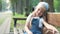 Small tired child girl sitting on a bench with closed eyes resting in summer park.