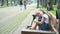 Small tired child girl sitting on a bench with closed eyes resting in summer park.