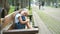 Small tired child girl sitting on a bench with closed eyes resting in summer park