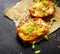 Small toast with melted cheese, scallions, chili peppers and fresh thyme on black background