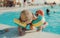 A small toddler boy with armbands and mother swimming in water on summer holiday.