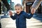 A small toddler boy with unrecognizable parents walking outdoors in city.