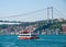 Small touristic  cruise ship with passengers at Bosporus strait residential buildings and second Bosporus bridge at coast