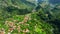 Small town at mountains near ocean during summer golden hour. Village aerial view landscape. Madeira, Portugal.