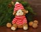 A small toy puppy in a red hat, walnuts and spruce branches next to it on old wooden background