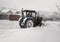 A small tractor clears the road from snow