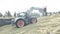 Small tractor digger arranging crushed corn mass for feeding cows in heap at livestock farm in Salitja on sunny day