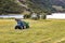 Small tractor with round baler haymaking on a field in Geiranger, Norway