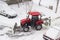 Small tractor snow plow in courtyard during snowfall