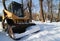 Small tractor with snowplough covered in snow in the park