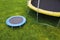 Small trampoline near big one with round mat, size comparison, green lawn background