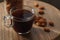 Small transparent cup of coffee surrounded by almonds on a tiny natural wood round table